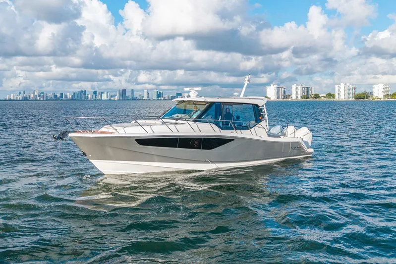  Yacht Photos Pics 2024 Boston Whaler 405 Conquest cruising on water with city skyline in background.