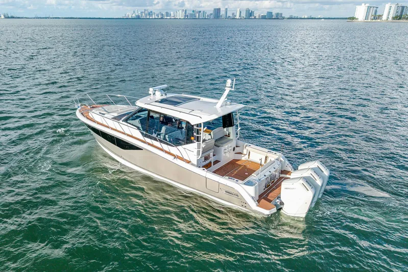  Yacht Photos Pics 2024 Boston Whaler 405 Conquest cruising on open water with city skyline backdrop.