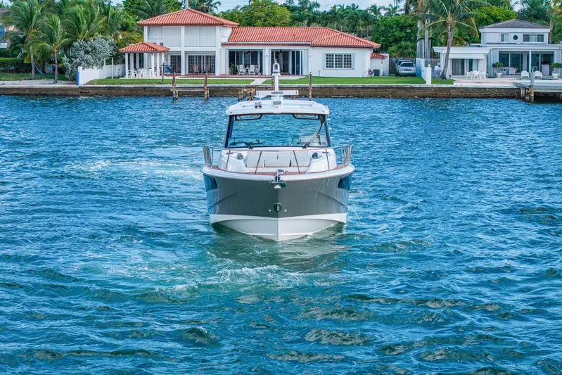  Yacht Photos Pics 2024 Boston Whaler 405 Conquest cruising on blue water near waterfront homes.