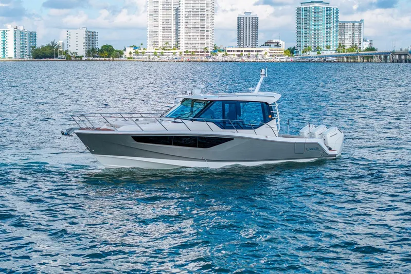  Yacht Photos Pics 2024 Boston Whaler 405 Conquest cruising on water with city skyline backdrop.