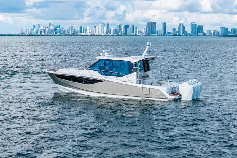  Yacht Photos Pics 2024 Boston Whaler 405 Conquest cruising on water with city skyline backdrop.