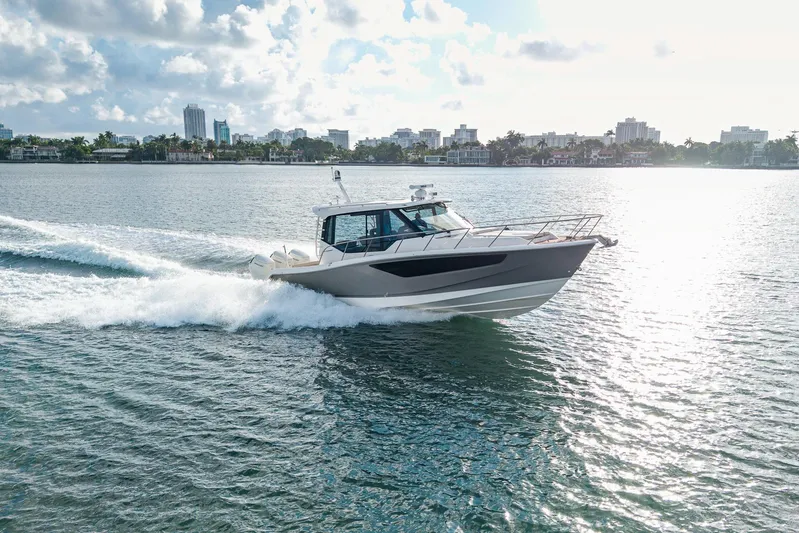  Yacht Photos Pics 2024 Boston Whaler 405 Conquest cruising on a sunny day near city skyline.