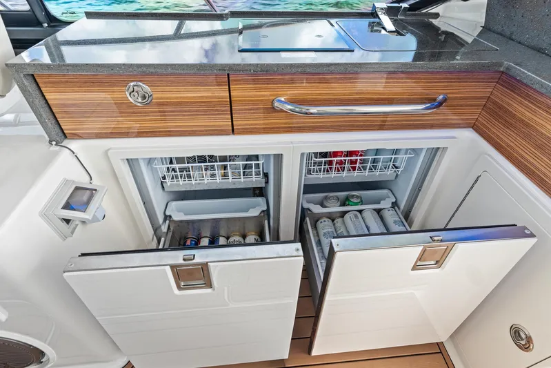  Yacht Photos Pics 2024 Boston Whaler 405 Conquest galley with open refrigerators and wooden cabinetry.