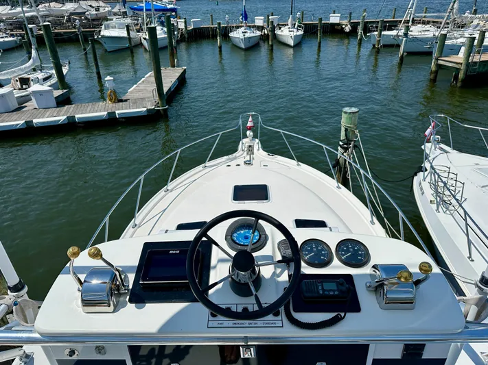  Yacht Photos Pics 2004 Tiara Yachts 3200 Open helm view at marina, showcasing controls and docked boats.