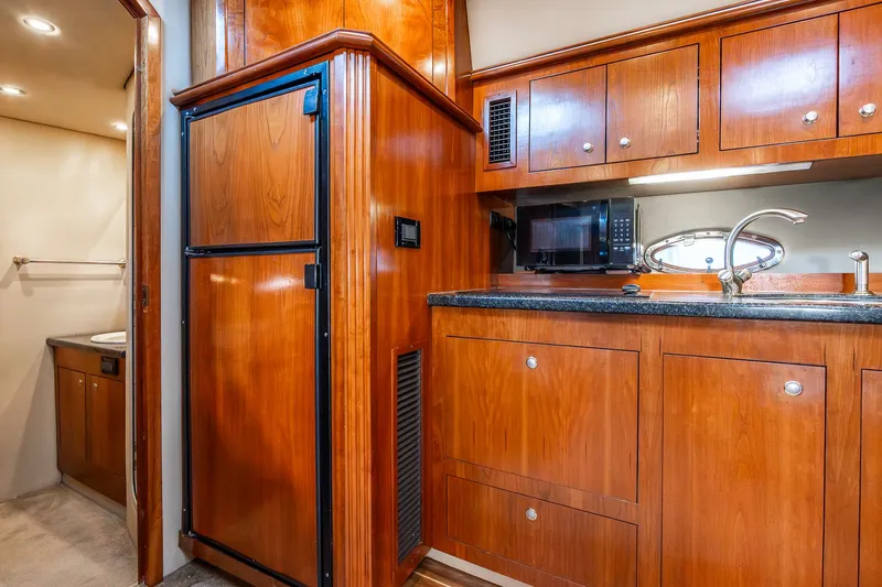 Escape Yacht Photos Pics 2005 Cruisers Yachts 440 Express kitchen with wood cabinetry, sink, microwave, and fridge.