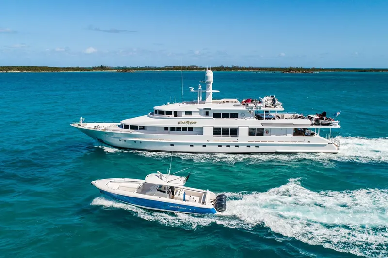 Starship Yacht Photos Pics Luxury yacht and speedboat cruising in clear blue ocean waters.