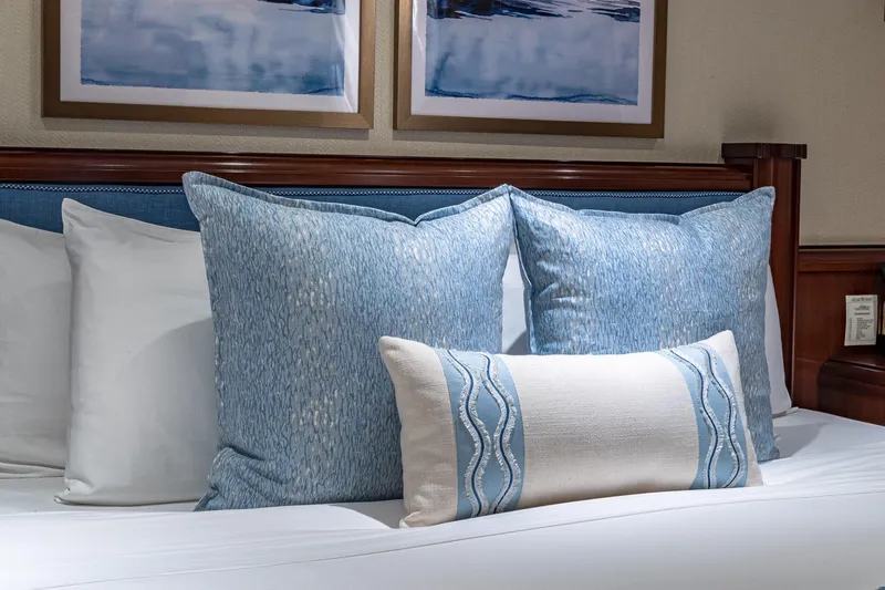Starship Yacht Photos Pics Luxurious bed with blue and white pillows, elegant wooden headboard, and framed artwork.