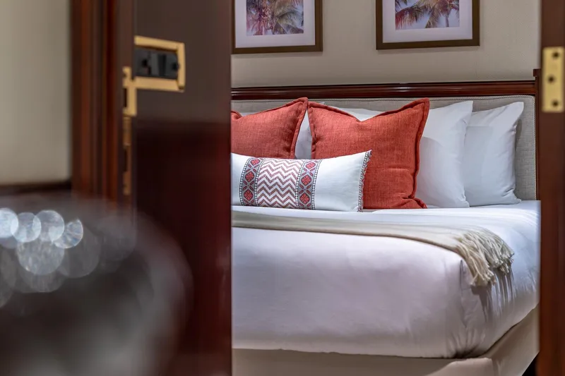 Starship Yacht Photos Pics Luxurious bedroom interior with red cushions on a bed, aboard a 1988 Van Mill Custom yacht.