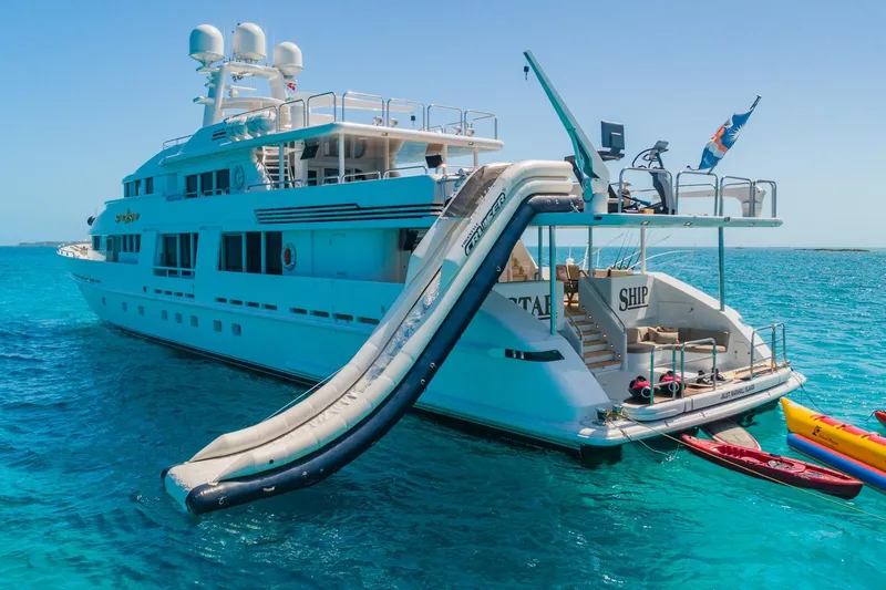 Starship Yacht Photos Pics Luxurious 1988 Van Mill Custom yacht with waterslide and kayaks in clear blue ocean.