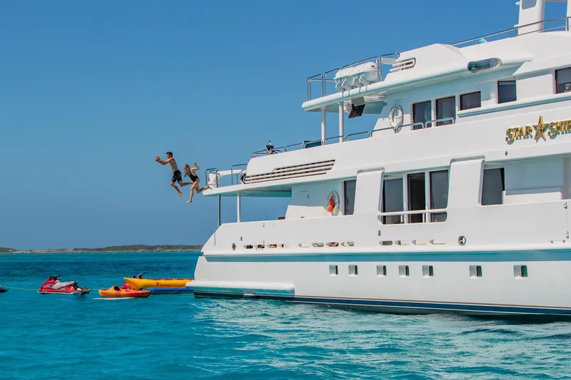 Starship Yacht Photos Pics Two people jumping off a 1988 Van Mill Custom yacht into the ocean, surrounded by kayaks.