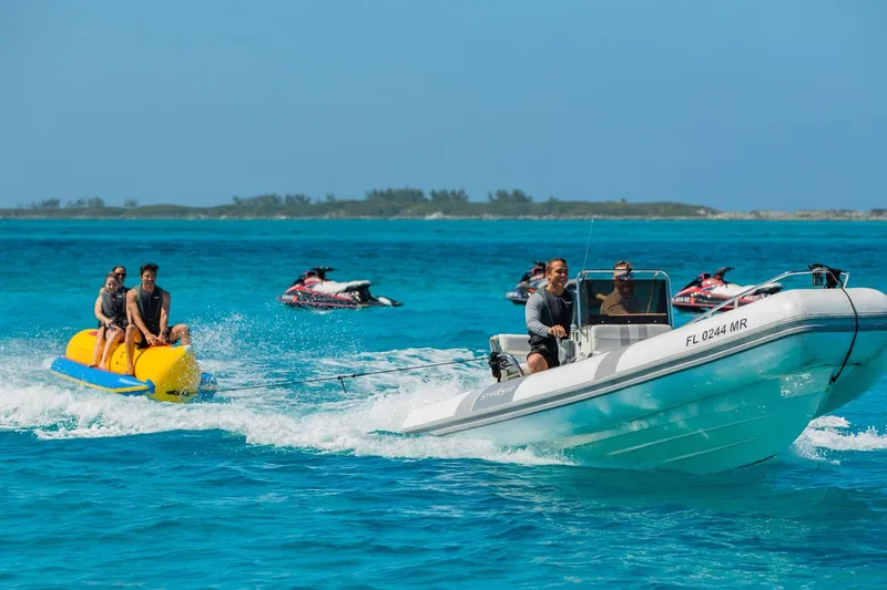 Starship Yacht Photos Pics Boat towing banana boat with riders on clear blue water, Van Mill Custom 1988.