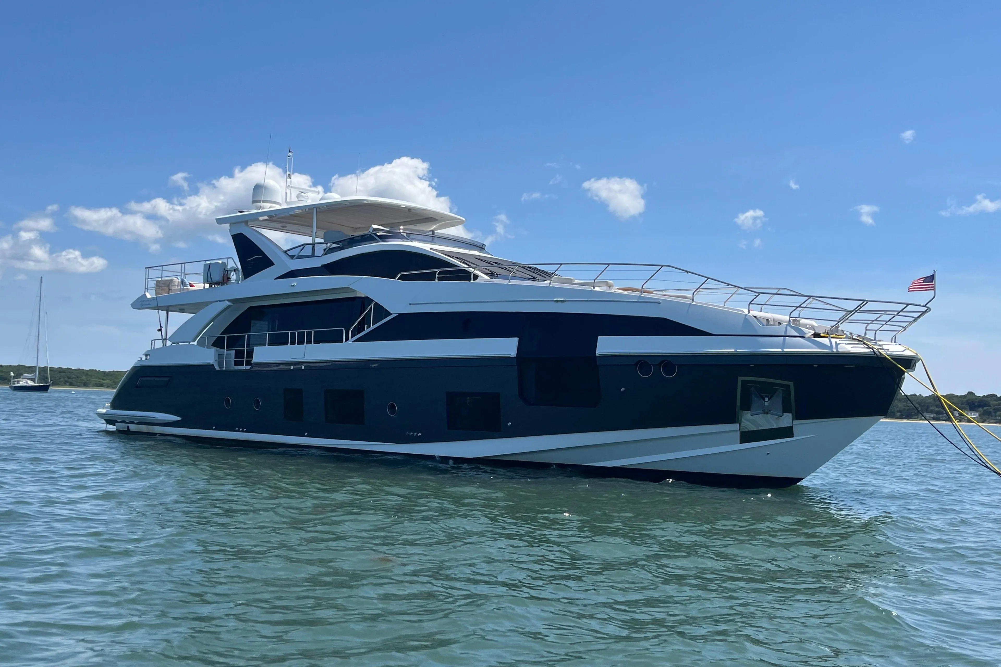 Luxurious 2019 Azimut Grande 27M yacht on calm waters under a clear blue sky.