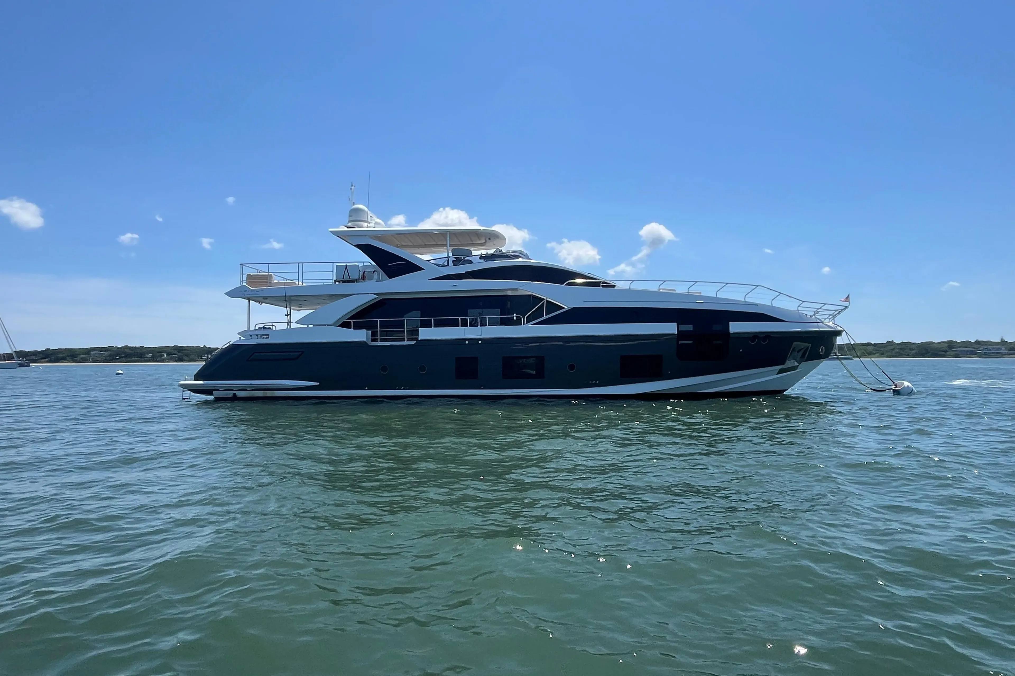 2019 Azimut Grande 27M yacht on calm water under clear blue sky.