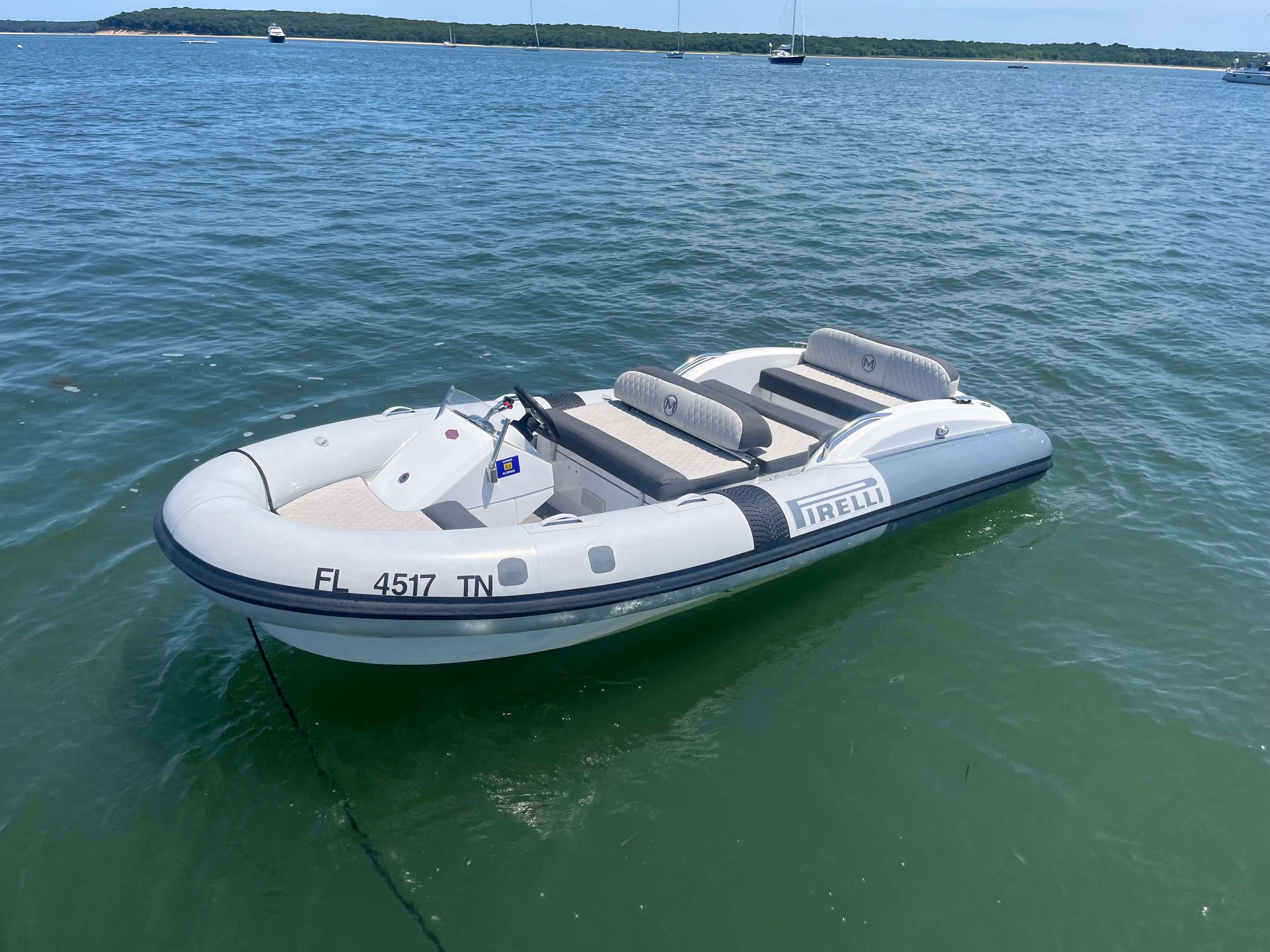 Inflatable boat on water, featuring Pirelli branding, near Azimut Grande 27M yacht.