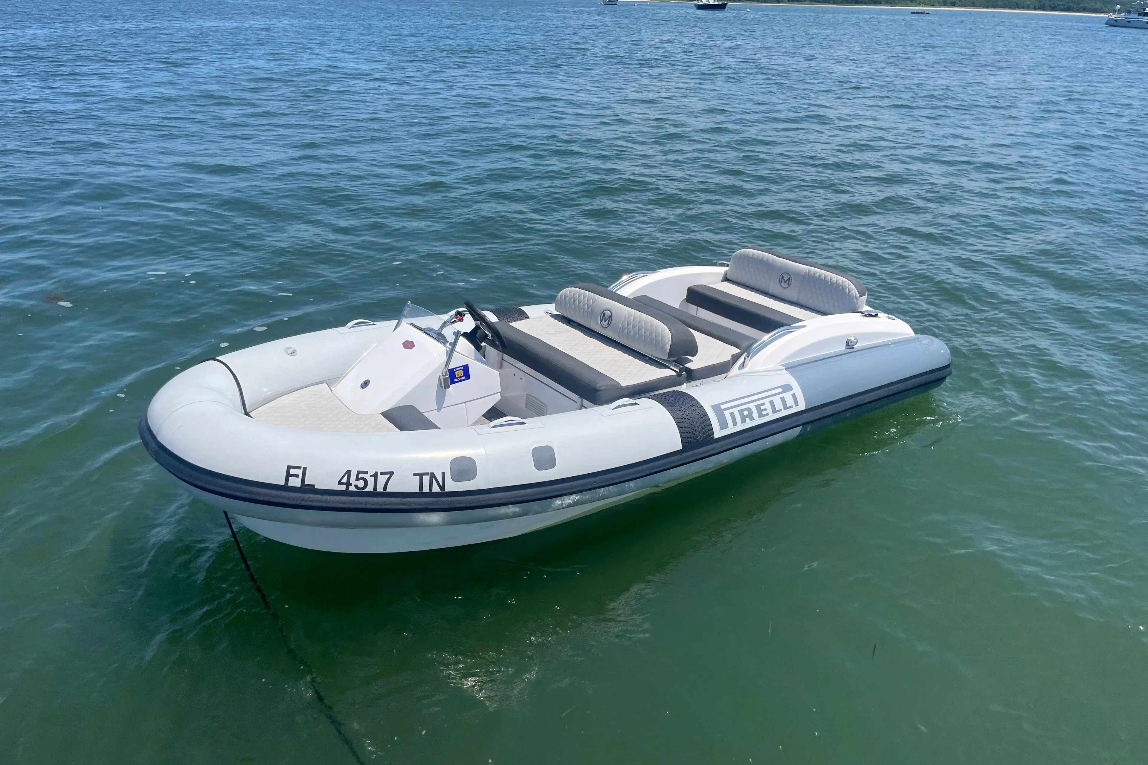 Inflatable boat on water, featuring Pirelli branding, near Azimut Grande 27M yacht.