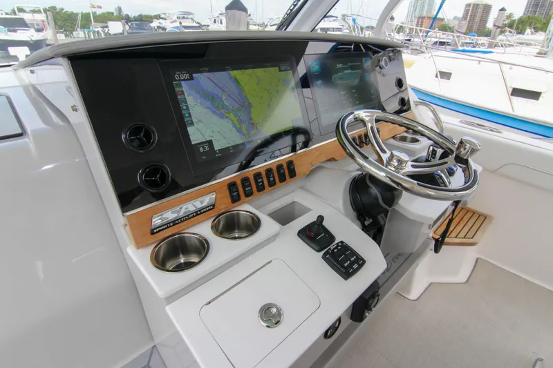  Yacht Photos Pics 2023 Regal 38 SAV helm with navigation screens and steering wheel in a marina setting.