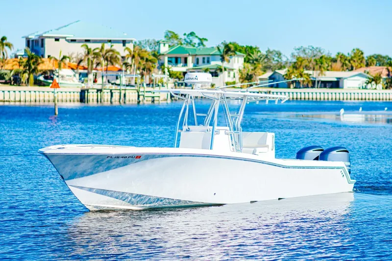  Yacht Photos Pics 2015 Invincible 33 Open Fisherman boat on calm water near coastal homes.