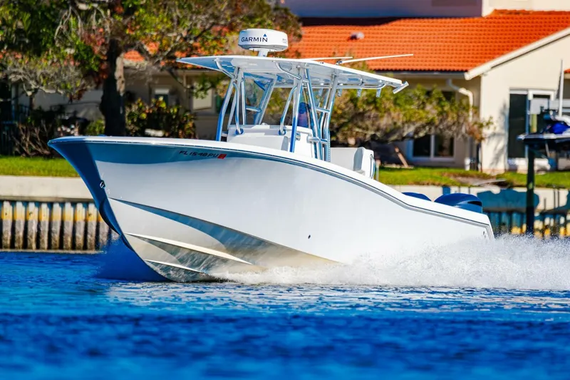  Yacht Photos Pics 2015 Invincible 33 Open Fisherman boat cruising on blue water near a coastal home.