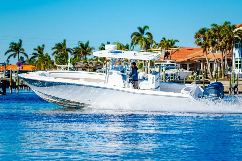  Yacht Photos Pics 2015 Invincible 33 Open Fisherman boat cruising on a sunny day near palm trees.
