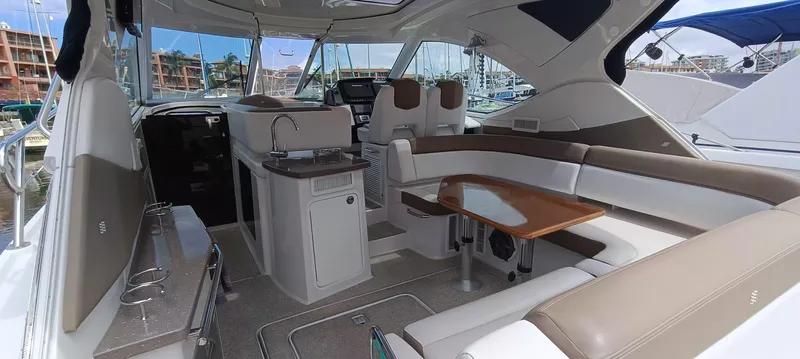 2016 Four Winns H440 Yacht Photos Pics 2016 Four Winns H440 yacht interior with seating, table, and kitchenette in a marina setting.