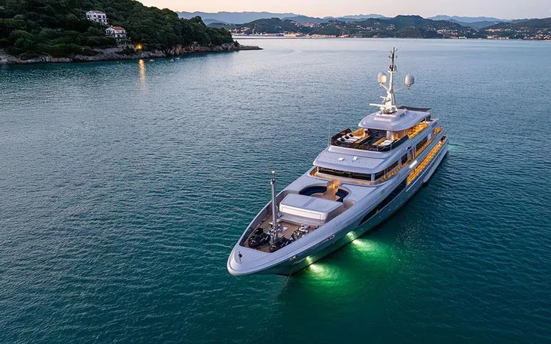 Luxurious 2019 Codecasa F74 yacht illuminated on serene waters at dusk.