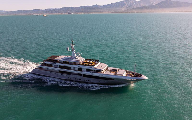 Luxurious 2019 Codecasa F74 yacht cruising on serene waters with mountainous backdrop.