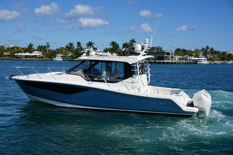 Rendezvous Yacht Photos Pics 2021 Boston Whaler 405 Conquest cruising on a sunny day with palm trees in the background.