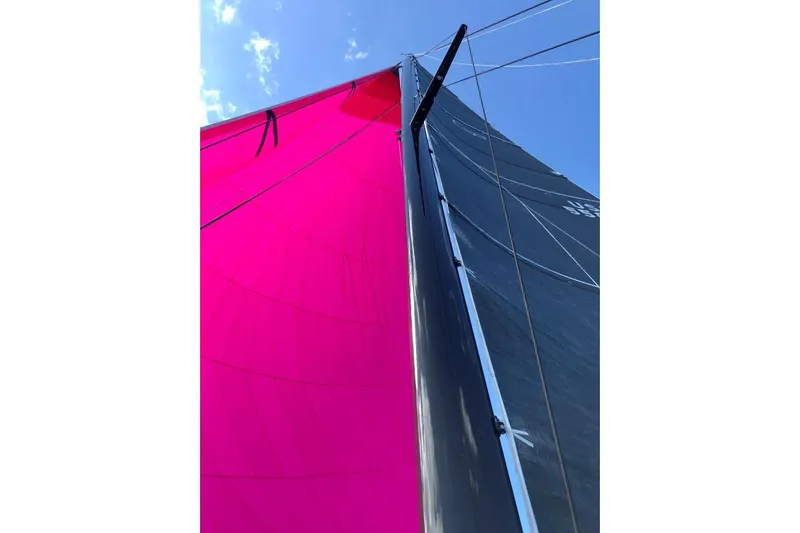 Vandal Yacht Photos Pics Gunboat 55 sailboat with vibrant pink and black sails against a clear blue sky.