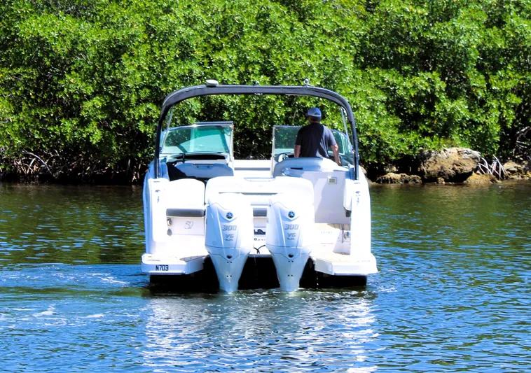 Sea M.a.j.i.c. Yacht Photos Pics 2022 Regal 33 OBX boat cruising on a sunny day near lush greenery.