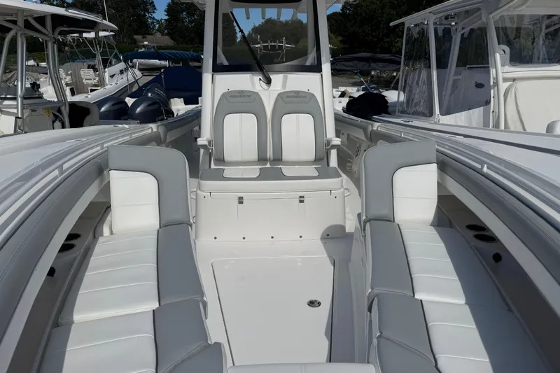  Yacht Photos Pics 2022 Regulator 31 boat interior with white seating and console, docked among other boats.