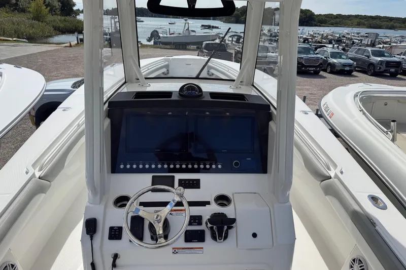  Yacht Photos Pics 2022 Regulator 31 boat dashboard with steering wheel and control panel, docked near a lake.