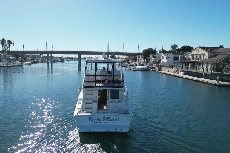 Reelin N Rockin Yacht Photos Pics 2003 Silverton 38 Convertible boat cruising in a sunny marina with bridge and waterfront homes.