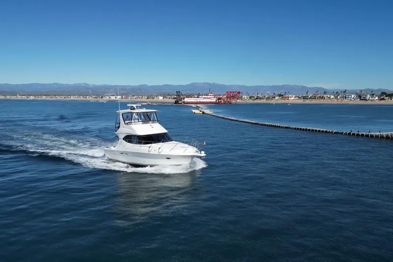 Reelin N Rockin Yacht Photos Pics 2003 Silverton 38 Convertible yacht cruising near a coastal cityscape.