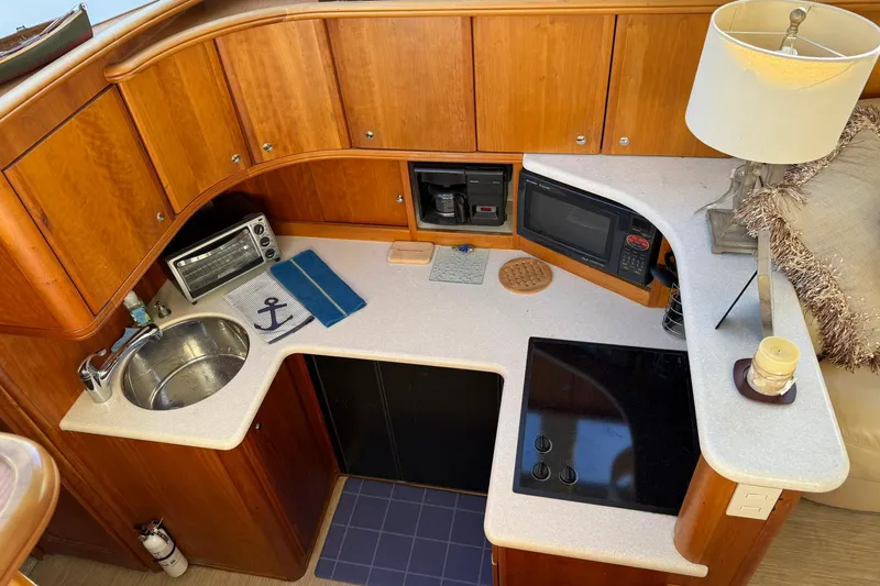 Reelin N Rockin Yacht Photos Pics 2003 Silverton 38 Convertible yacht kitchen with sink, stove, microwave, and wooden cabinetry.