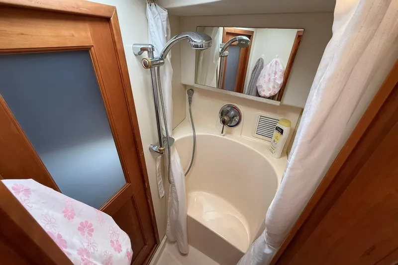 Reelin N Rockin Yacht Photos Pics 2003 Silverton 38 Convertible yacht bathroom with shower, wooden door, and mirror.