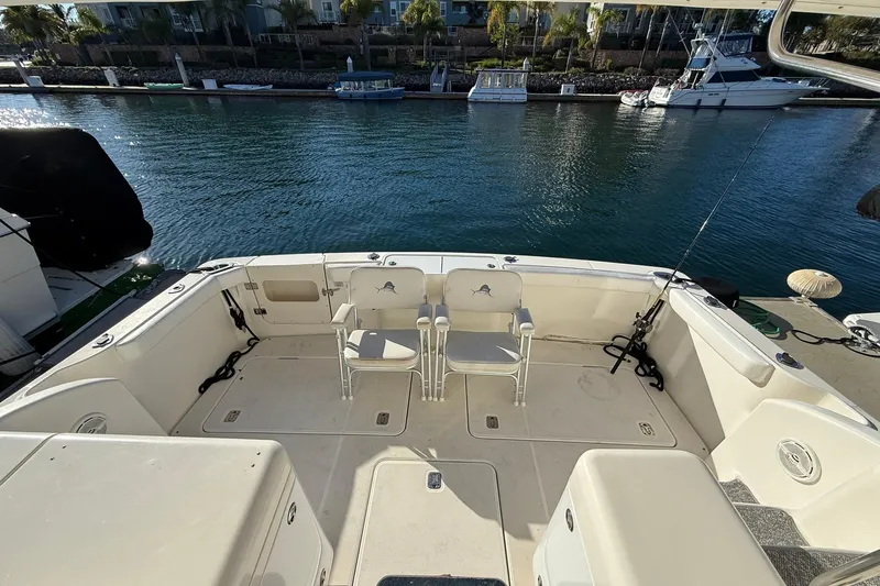Reelin N Rockin Yacht Photos Pics 2003 Silverton 38 Convertible boat deck with chairs, docked by calm waters.