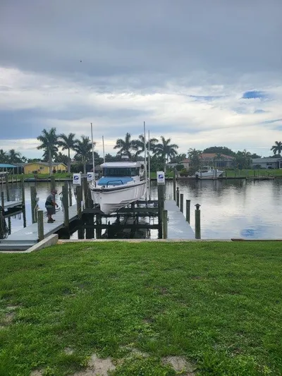  Yacht Photos Pics 2024 Axopar 37 XC CROSS CABIN docked by a serene waterfront with palm trees.