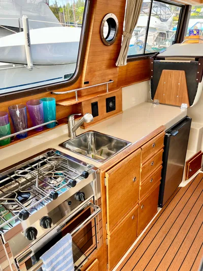 Yacht Photos Pics 2018 Ranger Tugs R-27 interior kitchen with stove, sink, and wooden cabinetry.