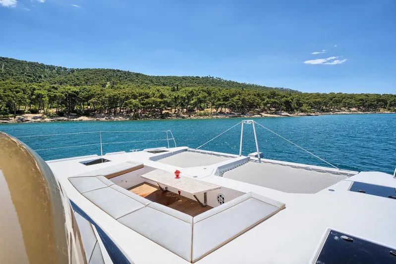 Orange Yacht Photos Pics Luxurious Luna 47 yacht deck with ocean view, 2023 model, near lush green coastline.