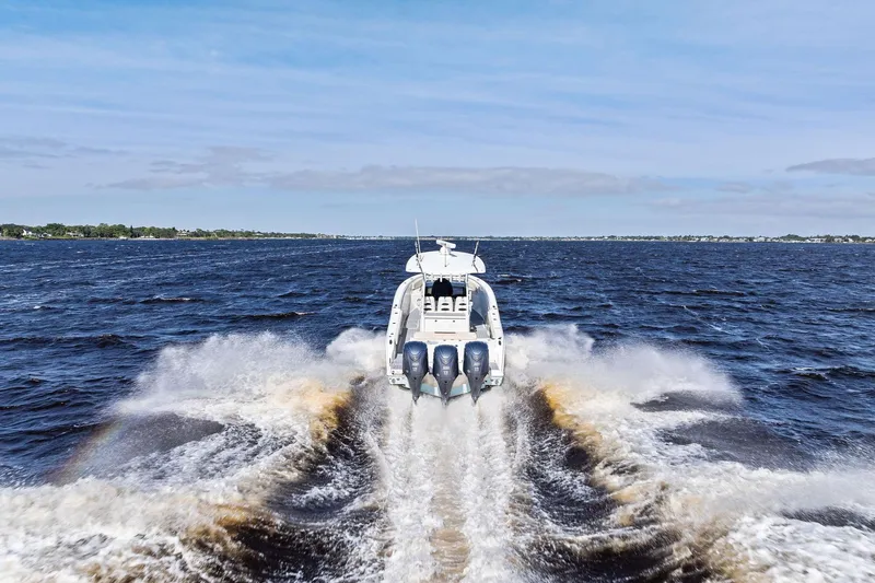 No Name Yacht Photos Pics 2023 Cobia 350 Center Console boat speeding on open water, rear view.