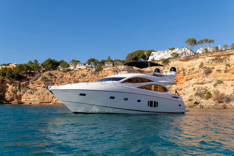  Yacht Photos Pics Sunseeker Manhattan 70 yacht from 2008 on clear blue water near rocky coastline.