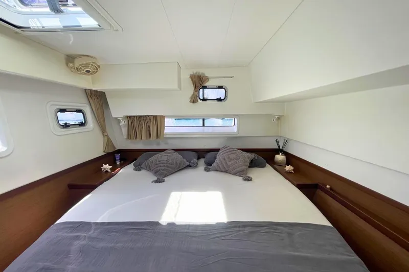 Lucky Vibes Yacht Photos Pics Luxurious cabin interior of a 2018 Lagoon 42 catamaran with cozy bedding and natural light.