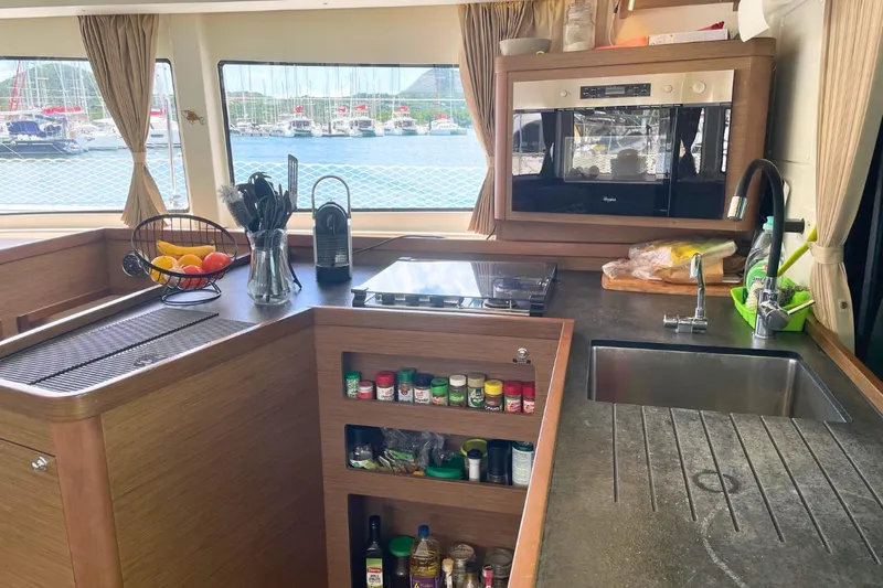 Lucky Vibes Yacht Photos Pics Modern kitchen interior of 2018 Lagoon 42 catamaran with appliances and marina view.