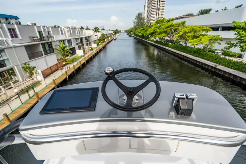 Bel Esprit Yacht Photos Pics Helm of 1999 Jim Smith Custom 66 Sportfish overlooking a canal with modern buildings.