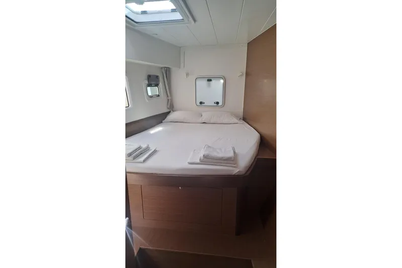  Yacht Photos Pics Cozy bedroom interior of 2020 Lagoon 42 catamaran with bed and porthole windows.