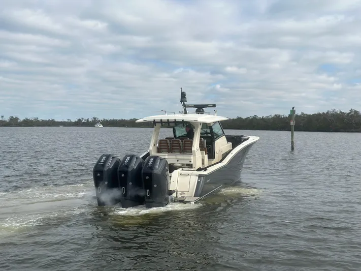  Yacht Photos Pics 2023 Scout 425 LXF boat cruising on a calm lake with triple outboard engines.