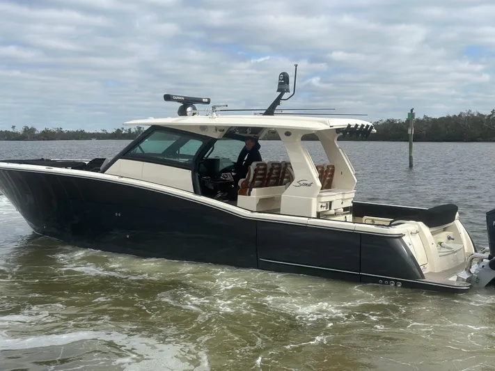  Yacht Photos Pics 2023 Scout 425 LXF boat cruising on a calm river under cloudy skies.