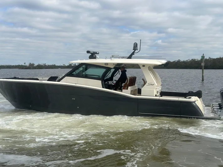  Yacht Photos Pics 2023 Scout 425 LXF boat cruising on a calm river under cloudy skies.