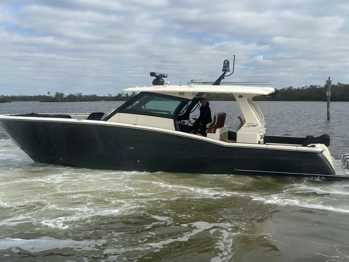 Yacht Photos Pics 2023 Scout 425 LXF boat cruising on a calm river under cloudy skies.