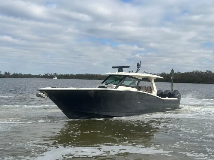  Yacht Photos Pics 2023 Scout 425 LXF boat cruising on a calm lake under cloudy skies.